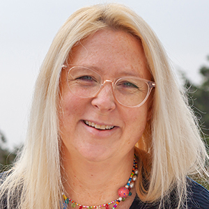 Headshot of Gabi Olson-Welsh wearing glasses and smiling into camera