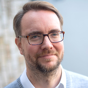 Head shot of Adam Fortune smiling and looking away from camera