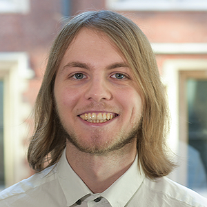 Headshot of Peter Stevens wearing a shirt and smiling into the camera