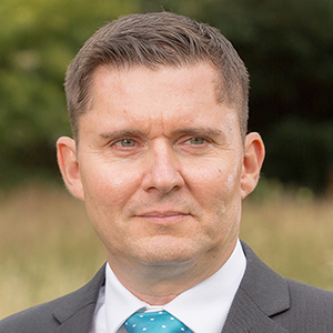 Headshot of Cory Bebb wearing a suit looking away from the camera