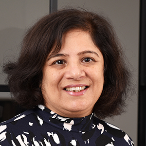 Headshot of Dhruti Thakrar wearing a black and white top looking to the side of the camera