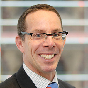 Headshot of Toby Ward wearing a suit smiling into the camera