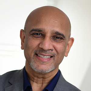 Headshot of Minesh Patel wearing a grey jacket looking at the camera