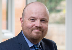 Head shot of Keith Gilbert smiling into camera