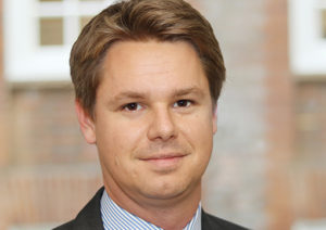 Headshot of Alex Boothman wearing a suit looking at the camera